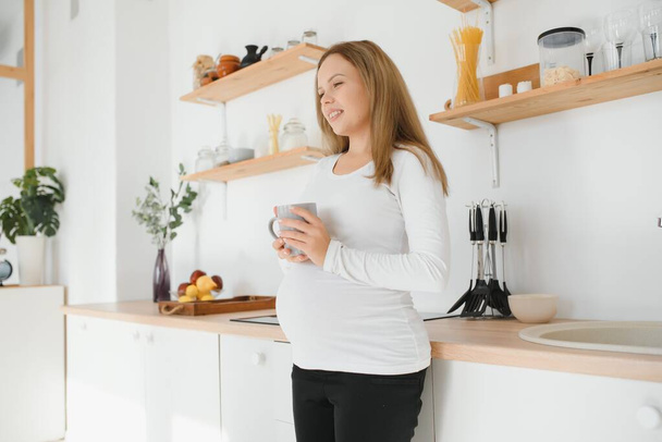 Pregnant woman in kitchen making salad - Photo, Image
