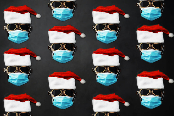 Sombrero, gafas y nariz de Santa Claus con mascarilla en fondo rojo. Concepto de celebración de Navidad o Año Nuevo. Reno de Navidad hecho de mascarilla protectora y decoraciones. Concepto de salud - Foto, imagen
