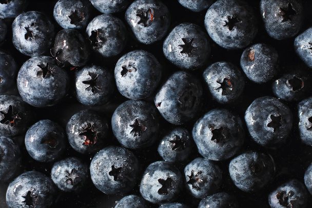 Вода падає на достиглий солодкий чорниця. Свіжі чорниці з копіювальним простором для вашого тексту. Веганська і вегетаріанська концепція. Macro texture of blueberry berries.Texture blueberry berries close up - Фото, зображення