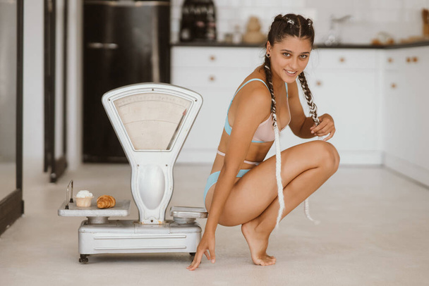 Woman in lingerie posing at the old grocery scales. Healthy eating concept - Photo, image