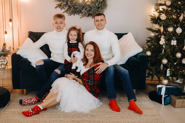 Close-up portrait of a happy family sitting on a sofa near a Christmas tree celebrating a holiday. - Foto, Imagem