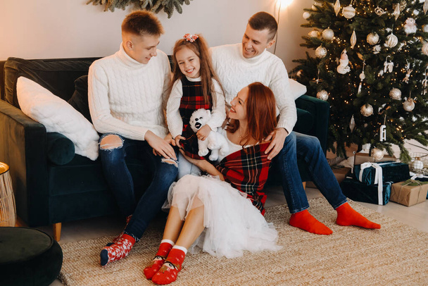 Close-up portrait of a happy family sitting on a sofa near a Christmas tree celebrating a holiday. - Photo, image