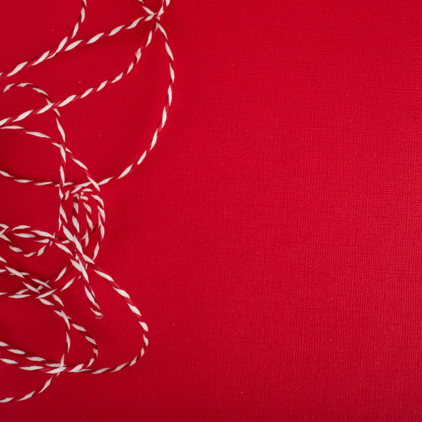 Abstract Christmas background of red paper and striped curly decorative traditional rope, copy space for text content - Valokuva, kuva