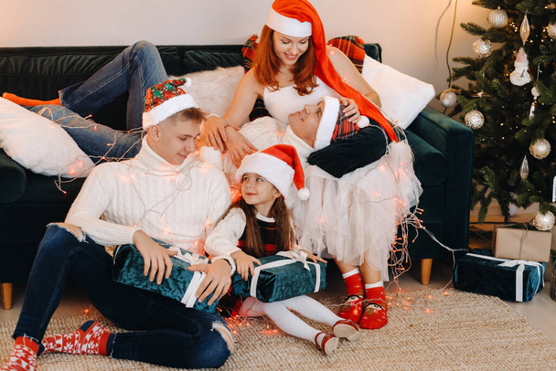 Close-up portrait of a happy family sitting on a sofa near a Christmas tree celebrating a holiday. - Φωτογραφία, εικόνα