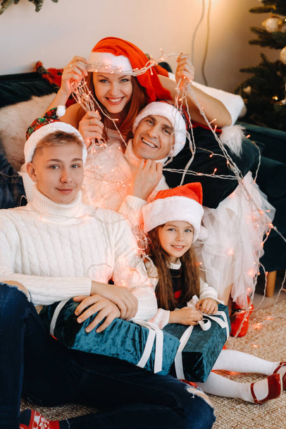 Close-up portrait of a happy family sitting on a sofa near a Christmas tree celebrating a holiday. - Foto, afbeelding