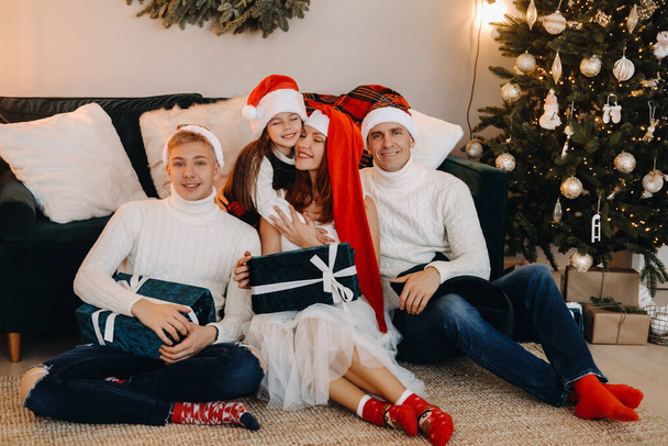 Close-up portrait of a happy family sitting on a sofa near a Christmas tree celebrating a holiday. - Foto, afbeelding