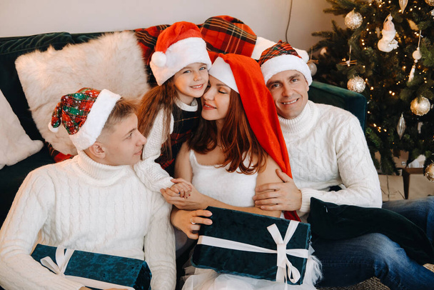 Close-up portrait of a happy family sitting on a sofa near a Christmas tree celebrating a holiday. - Foto, immagini