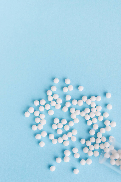 Homeopathic pills and plastic container on a blue background. Homeopathic medicine - Photo, Image