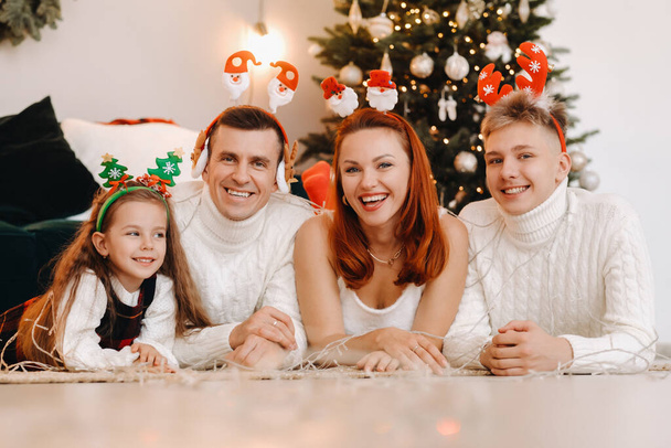 Close-up portrait of a happy family lying near a Christmas tree celebrating a holiday. - Foto, afbeelding