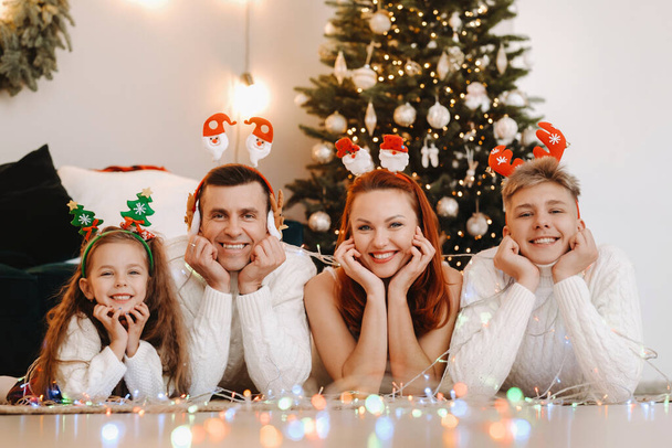 Close-up portrait of a happy family lying near a Christmas tree celebrating a holiday. - Photo, Image
