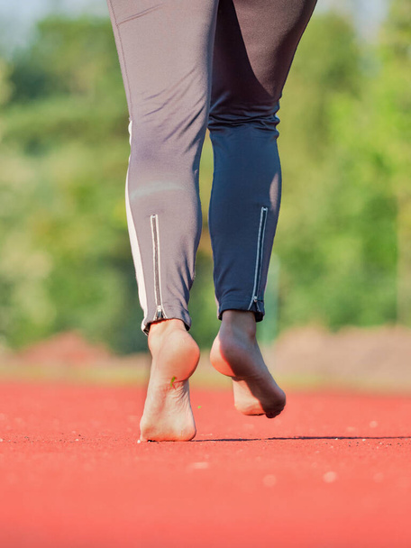 Bare πόδια θηλυκό γυμναστήριο μοντέλο τρέχει και τρέξιμο προπόνηση. Αθλητικός τρόπος ζωής. Απλώνοντας γυμνά πόδια και αστραγάλους.  - Φωτογραφία, εικόνα