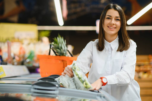 Woman grocery shopping and looking very happy - Foto, imagen