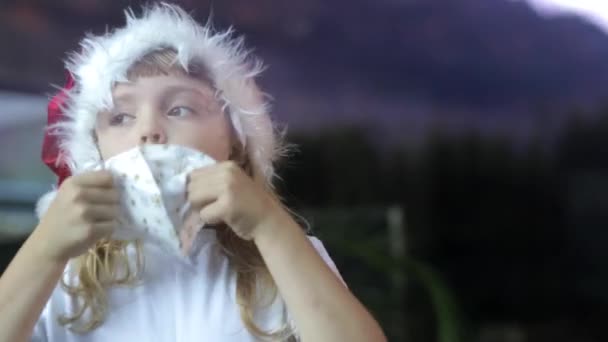 Chica de 6 años en el sombrero de Santa se pone la máscara - Imágenes, Vídeo