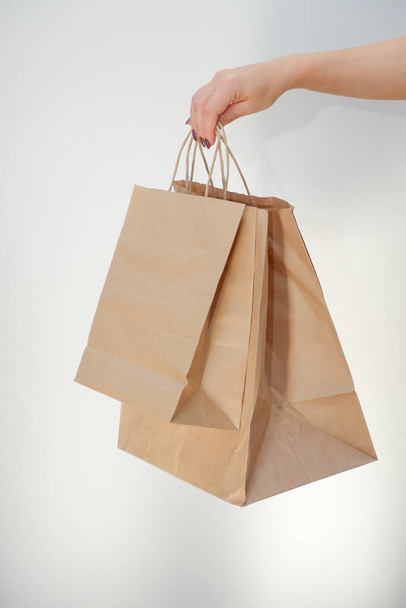 Ecological packaging. A cute unrecognizable woman hands you eco bags made of recycled paper. Shopping concept, natural materials, ecological style concept - Foto, immagini