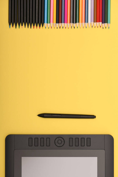 Monitor gráfico de lápiz en la mesa de color amarillo. Tablet PC negro con pantalla en blanco. Foto de alta resolución. Profundidad total del campo. Concepto de entorno de trabajo - Foto, imagen