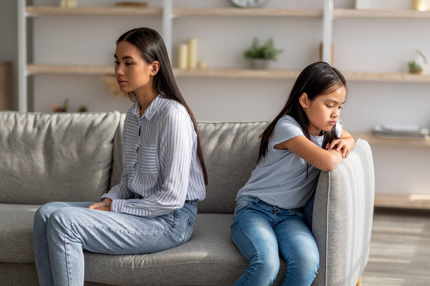 Triste asiático senhora mãe e chateado fêmea criança filha, tendo luta, briga, mal-entendido, sentados juntos no sofá - Foto, Imagem