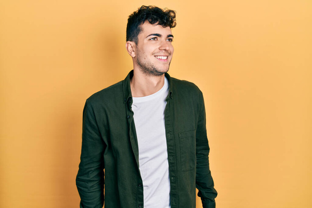 Fiatal spanyol férfi alkalmi ruhát visel, oldalra néz mosollyal az arcán, természetes kifejezéssel. nevetés magabiztos.  - Fotó, kép