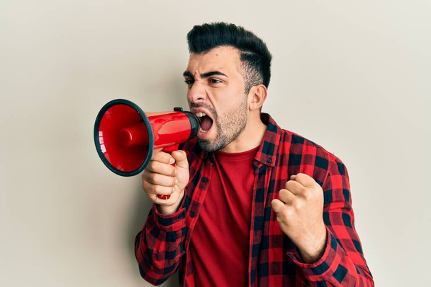 Ισπανόφωνος άντρας με γενειάδα ουρλιάζοντας με μεγάφωνο - Φωτογραφία, εικόνα