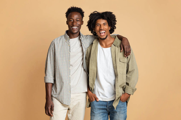 Concept d'amitié masculine. Deux gars noirs heureux embrassant et souriant à la caméra - Photo, image