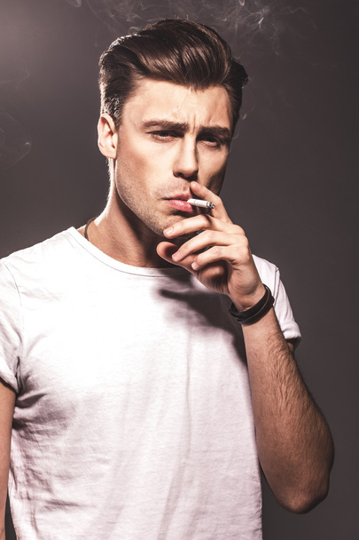 Handsome young man smoking cigarette - Foto, imagen
