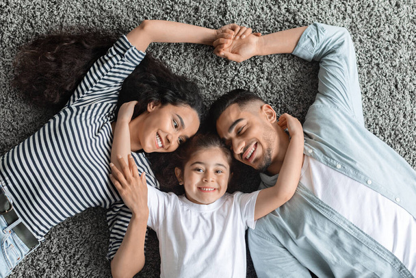 Portret szczęśliwej bliskowschodniej rodziny przytulającej się na podłodze - Zdjęcie, obraz