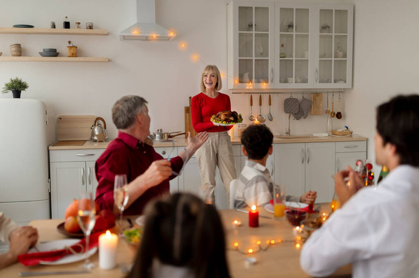 Boldog idős nő szolgálja nyaralás pulyka nagy kiterjedésű család, ünnepli hálaadás vagy karácsony otthon - Fotó, kép