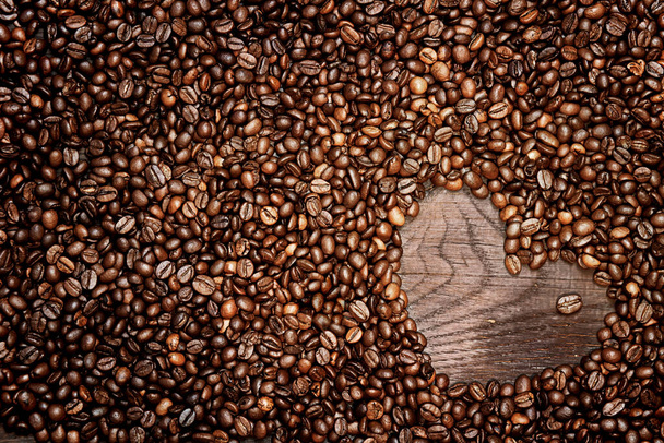 Chicchi di caffè disposti a forma di cuore su vecchio sfondo di legno - Foto, immagini