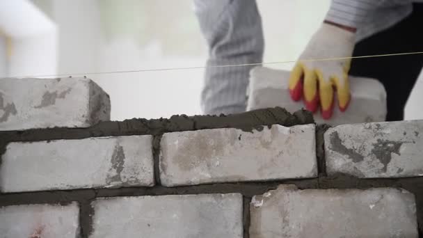 Maurer montiert Ziegelmauerwerk an der Außenwand. Professioneller Bauarbeiter verlegt Ziegel. - Filmmaterial, Video
