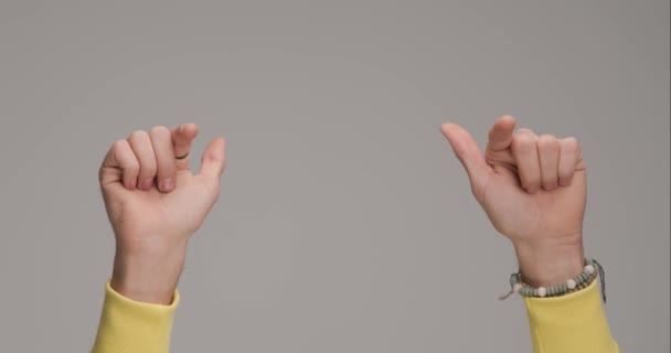 ręce faceta robiące kciuki w górę znak, wskazujące palce, wykonujące gest pokoju i bijące brawo na szarym tle - Materiał filmowy, wideo