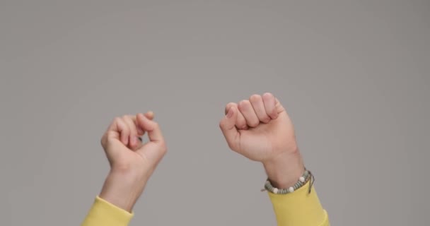 Руки молодого человека с кольцами и браслетами нумерацией от 1 до 10 и аплодисментами на сером фоне в студии - Кадры, видео