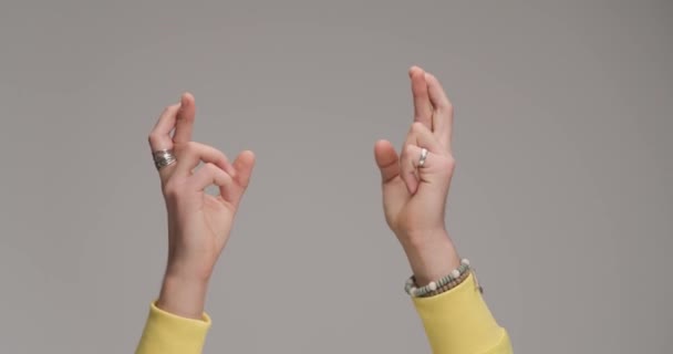 jonge man handen maken ongeluk gebaar en wensen geluk in de voorkant van grijze achtergrond in de studio - Video