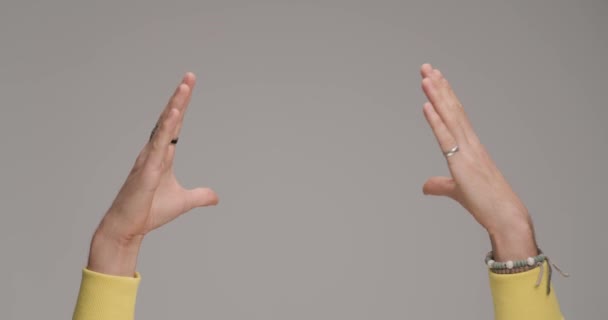guy 's handen met armbanden maken hart gebaar en tonen romantiek in de voorkant van grijze achtergrond in studio - Video