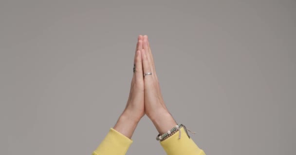 az ember keze imádkozik, keresztbe teszi az ujjait és balszerencsét jelez, sok szerencsét kíván a szürke háttér előtt a stúdióban - Felvétel, videó