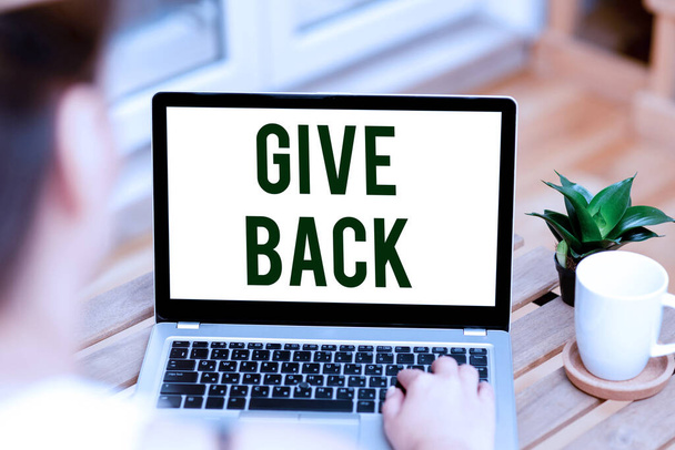 Inspiration showing sign Give Back. Business showcase the act of giving someone something that they owned or had before Woman Typing On Laptop Beside Coffe Mug And Plant Working From Home. - Photo, Image
