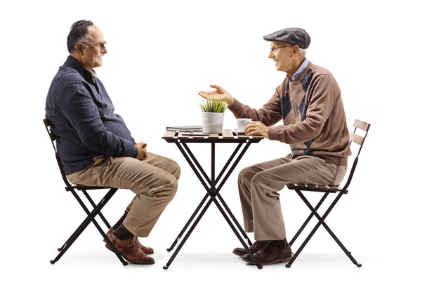Two elderly men sitting at a cafe table and having a conversation isolated on white background - Fotografie, Obrázek