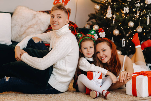 una famiglia felice è sdraiata sul pavimento della casa con i regali di Capodanno, accanto all'albero di Natale, - Foto, immagini