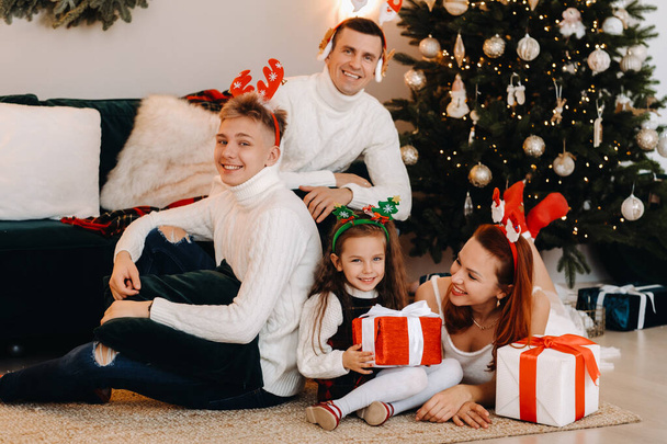 Happy family near the Christmas tree with gifts. - Zdjęcie, obraz