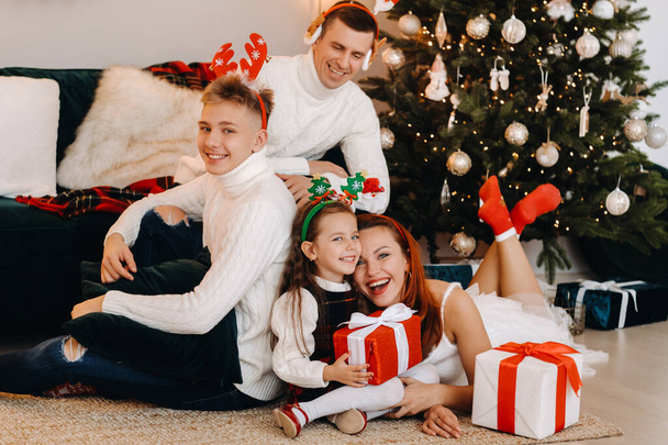 Happy family near the Christmas tree with gifts. - 写真・画像
