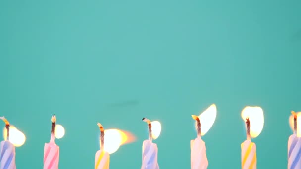 Concepto de Feliz Cumpleaños Hecho de Velas de colores ardientes sobre fondo azul o turquesa. Apagando velas de cumpleaños de 7 años. Cámara lenta full HD de vídeo. - Imágenes, Vídeo