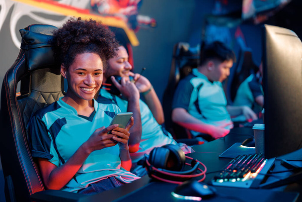 Happy woman joue à des jeux vidéo en ligne professionnellement dans un cybercafé - Photo, image