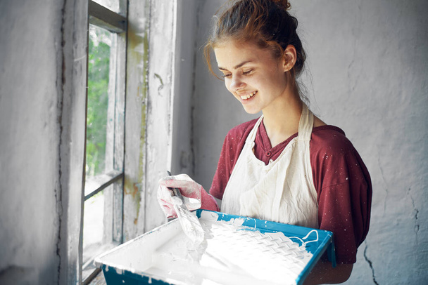 woman in apron painter repair painting window - Foto, afbeelding