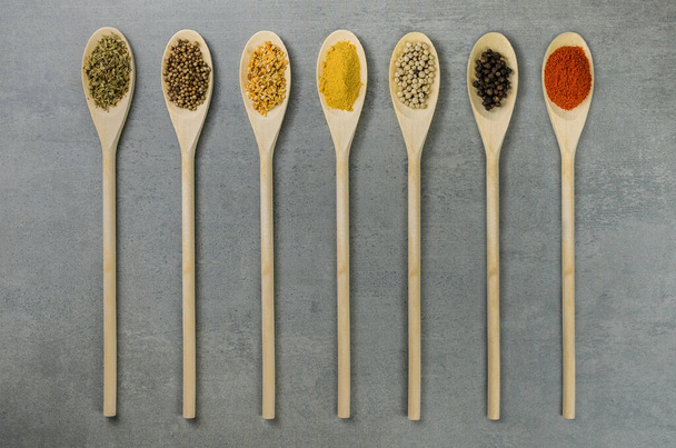 Various spices in wooden spoons side by side seen from above - Foto, Imagen