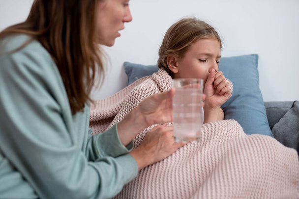 Mère met une tablette gazeuse dans l'eau et donne cette boisson à sa fille malade - Photo, image