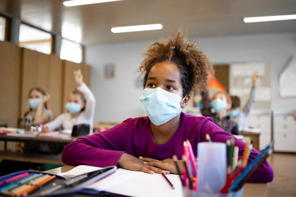 School children wearing face mask in classroom during corona virus pandemic. - Foto, afbeelding