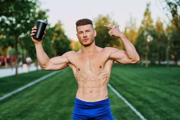 athletic man with pumped up muscular body in the park exercise workout motivation - Foto, Imagen
