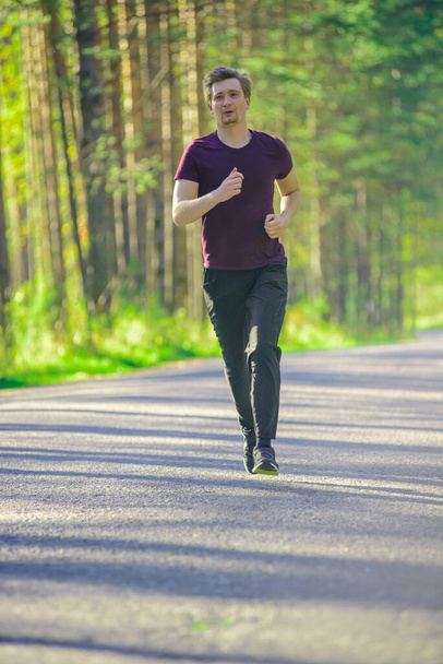 Man jogging in city partk at beautiful summer day. Sport fitness model caucasian ethnicity training outdoor. - 写真・画像