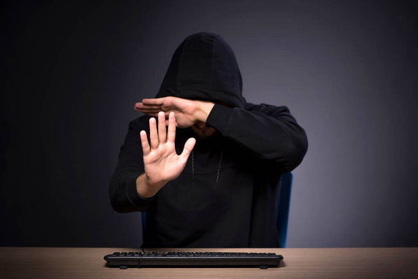 Jonge mannelijke hacker op grijze achtergrond - Foto, afbeelding