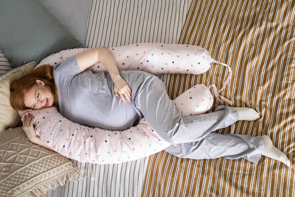 Top view happy future mother lying on comfortable bed hugging pillow for pregnant relaxing - Foto, immagini