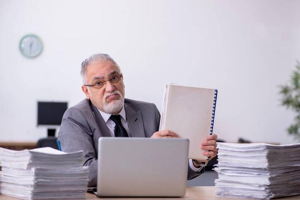 Старий чоловік-працівник незадоволений надмірною роботою в офісі
 - Фото, зображення