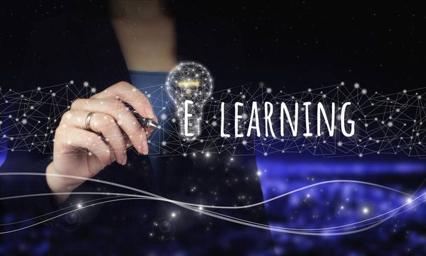 E-learning Internet Education Webinar Online Courses.Hand holding digital graphic pen and drawing digital hologram light bulb sign, e-learning on city dark blurred background - Photo, Image